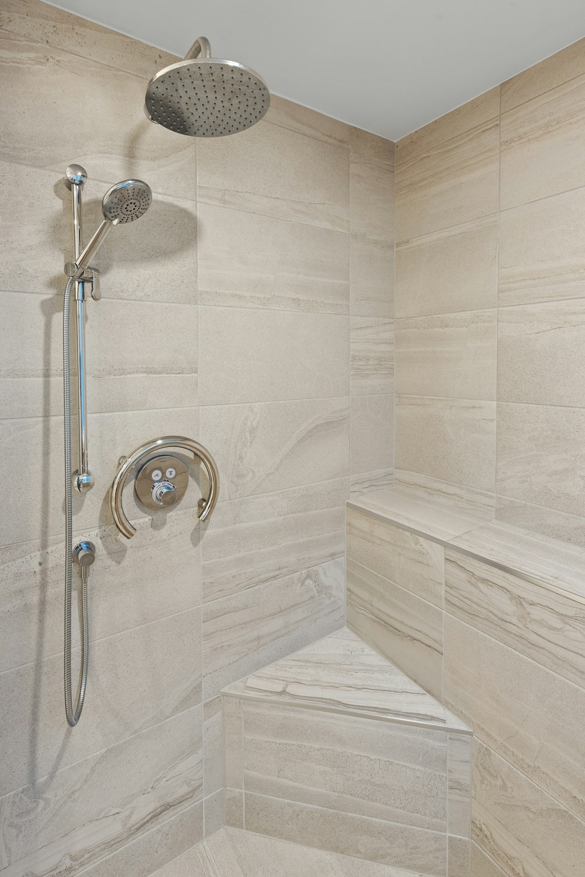 A walk-in tiled shower with a built-in bench and support bar