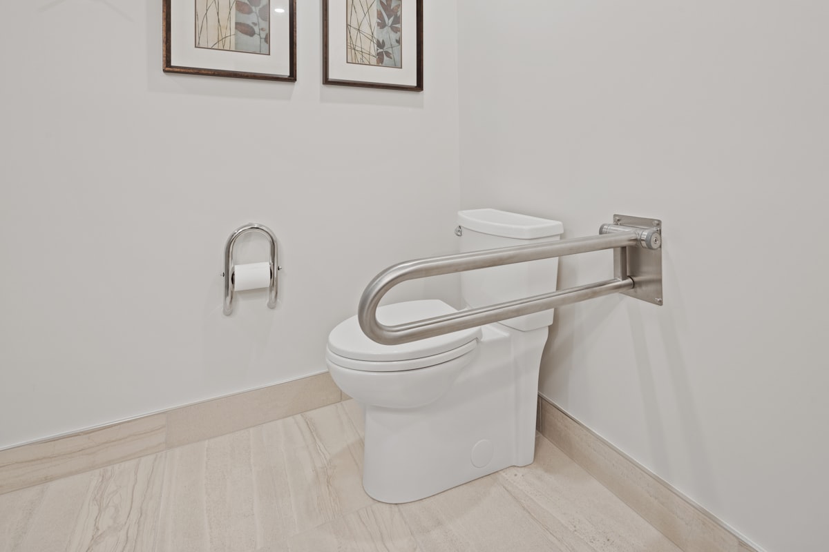 A bathroom with a fold-down grab bar installed beside the toilet
