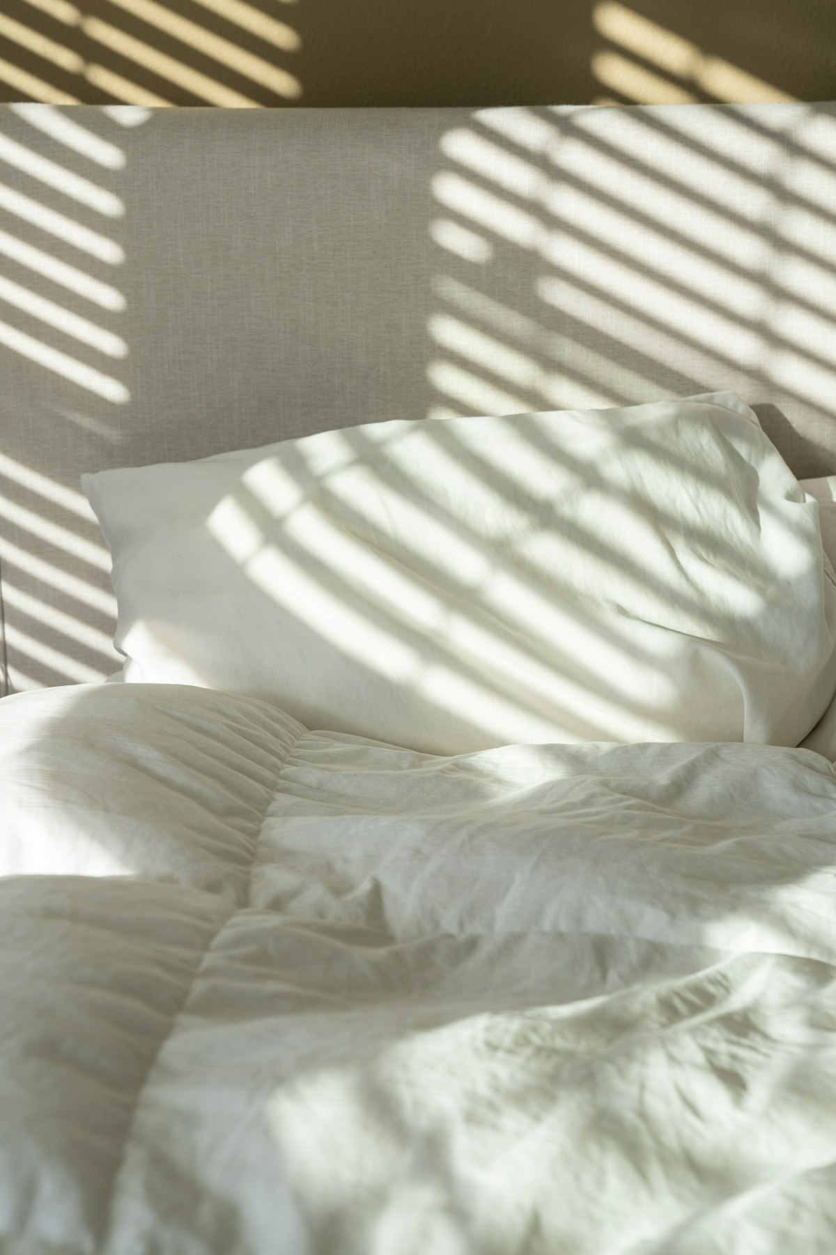 Soft morning light falling on a neatly made bed