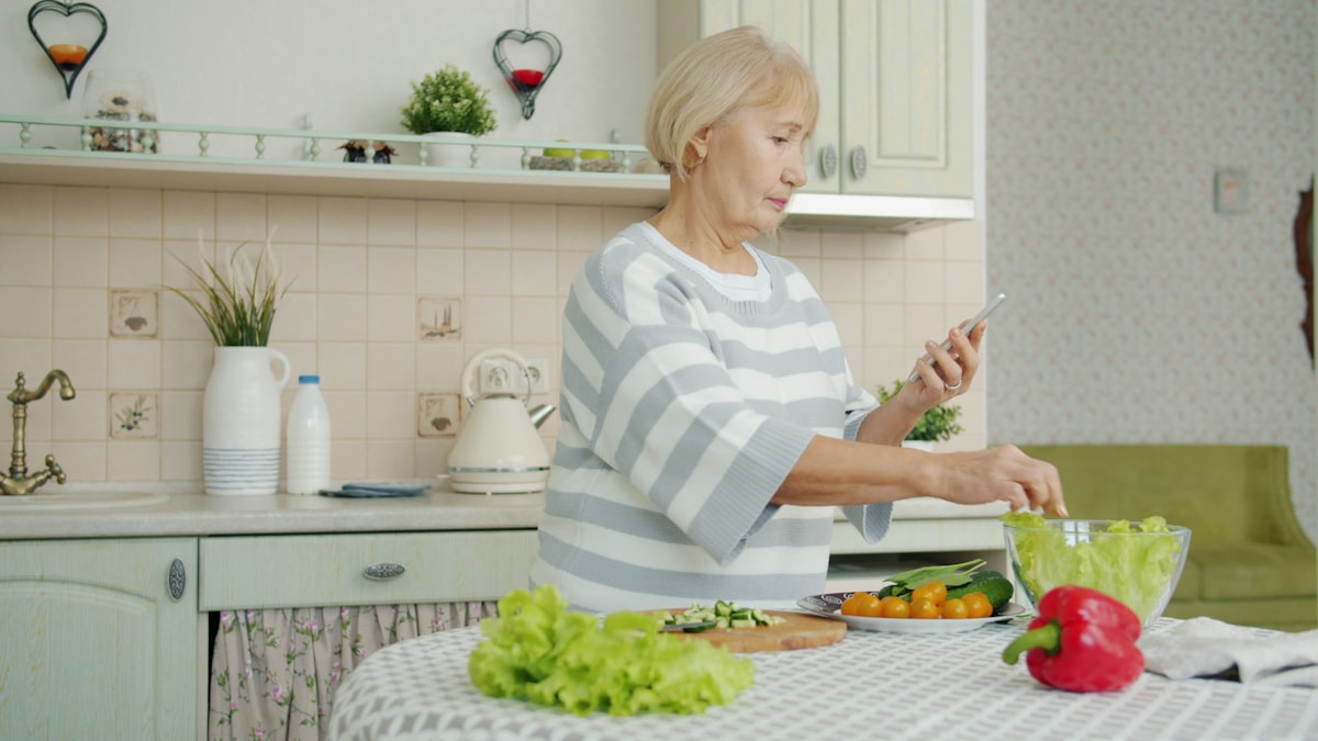 An older woman preparing a fresh salad in her bright kitchen