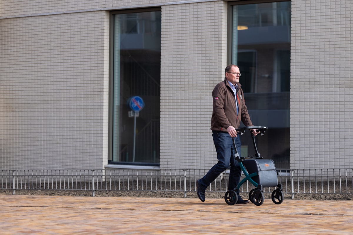 An older man walking confidently outdoors with a rollator